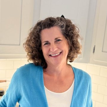 Mary Ann Kelley standing in a kitchen with white cabinets and countertops.